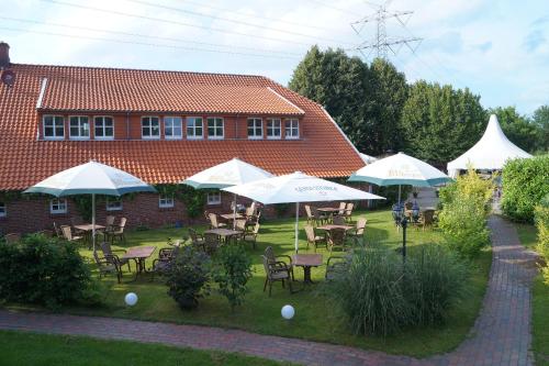 un grupo de mesas y sillas con sombrillas en un patio en Gasthuus Ulenhoff, en Westoverledingen