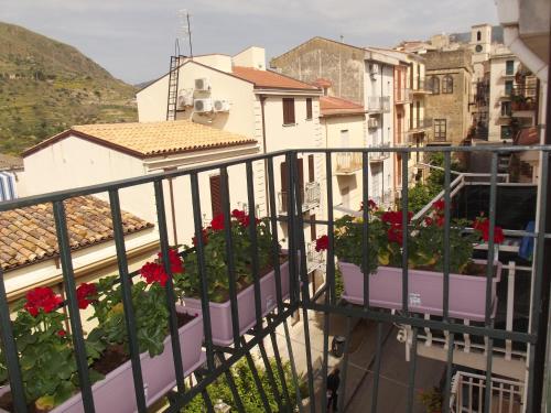 a balcony with red flowers and buildings at Le Due Sicilie B&B in Lascari
