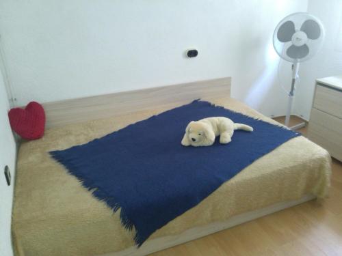 a white puppy laying on a blue blanket on a bed at Guest House Kachaka in Pleven