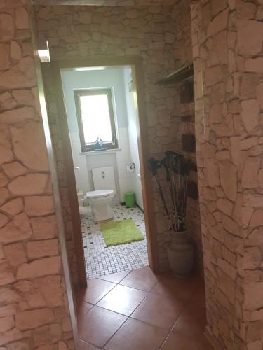 a bathroom with a toilet and a stone wall at Ferienwohnung La Le Lu in Hemfurth-Edersee
