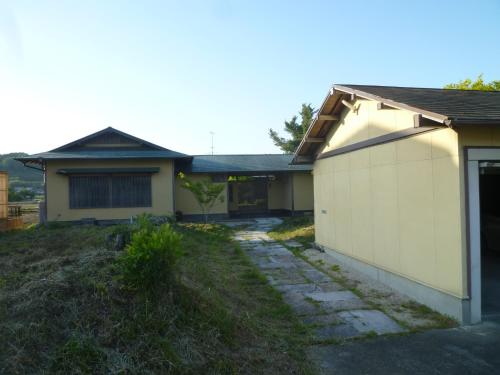 a house with a garage next to a building at Wakihonjin in Kikugawa