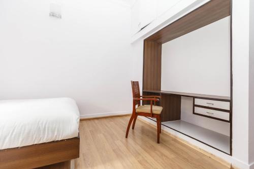 a bedroom with a bed and a chair and a mirror at Locul Uptown - Near Bangalore Palace Grounds in Bengaluru