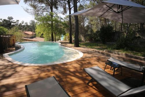 une piscine avec un parasol, une table et des chaises dans l'établissement Mas du Puech Cymbale, à Assas