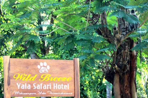 a sign for a hotel in front of a tree at Wild Breeze in Tissamaharama