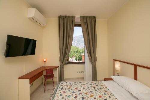 um quarto de hotel com uma cama, uma secretária e uma janela em B&B Ponte Capograssi em Sulmona