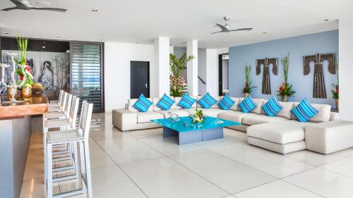 a living room with white furniture and blue pillows at Ocean's 11 Villa in Ban Pa Khlok