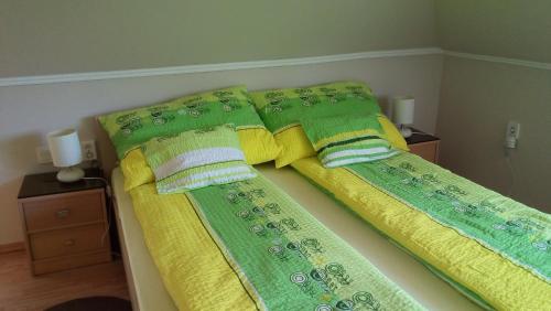 2 camas con sábanas y almohadas verdes y amarillas en Zöld Sziget Apartman en Gyula