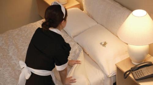 una donna in piedi accanto a un letto in una stanza d'albergo di Hotel Astra a Cattolica