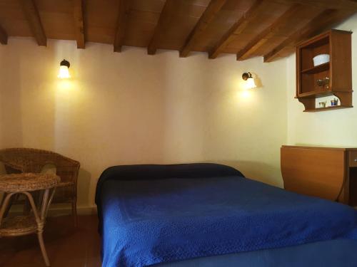 una camera con un letto blu e una sedia di La Rocca Chianti Hospitality a Tavarnelle in Val di Pesa