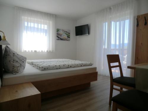 a bedroom with a bed with a chair and a window at Garni Pircher in Tirolo