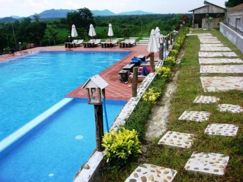 een zwembad met stoelen en parasols naast een resort bij Memoria Palace & Resort in Pailin