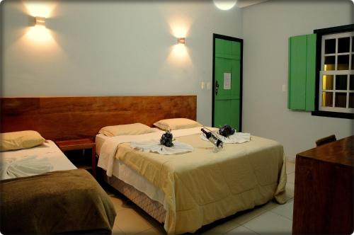 um quarto com duas camas e uma porta verde em Pousada Solar dos Guaras em Catas Altas