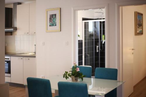 a kitchen with a table and blue chairs at Apartments Dvor - ap1, ap2, ap3 in Baška Voda