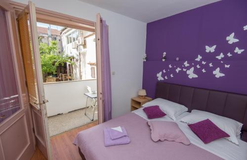 un dormitorio con una pared púrpura con mariposas. en Apartment Nekić, en Zadar