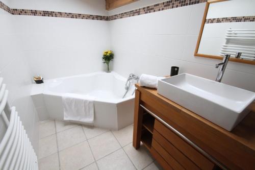 a white bathroom with a tub and a sink at Aiglon Morzine in Morzine
