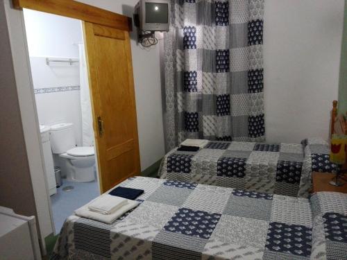 a bathroom with two beds in a room with a toilet at Hostal Villa Mercedes in Chipiona
