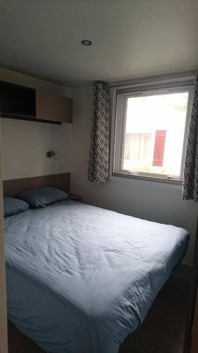 a bedroom with a large bed with a window at Mobile Home dans Domaine de Kerlann in Pont-Aven