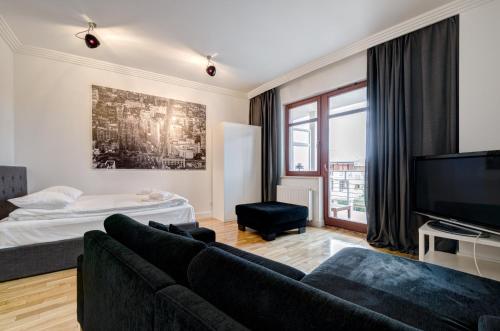 a living room with a couch and a tv at Dom & House - Apartamenty Neptun Park in Gdańsk