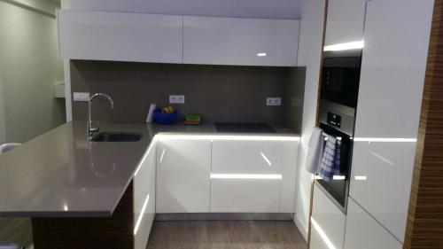 a white kitchen with a sink and a refrigerator at Piso en Monasterio de Caaveiro in A Coruña
