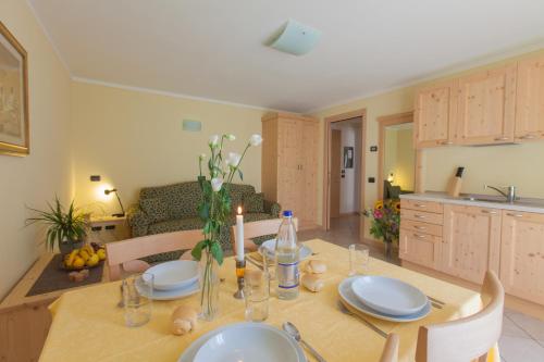 a kitchen and dining room with a wooden table with plates and candles at Residence Hotel Raggio Di Luce in Ponte di Legno