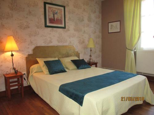 Un dormitorio con una cama grande con almohadas azules. en Gîte de Bazeille, en Saint-Avit-Sénieur