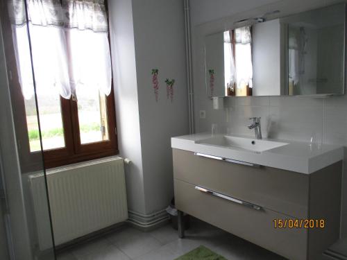 Un baño con lavabo, espejo y ventana. en Gîte de Bazeille, en Saint-Avit-Sénieur