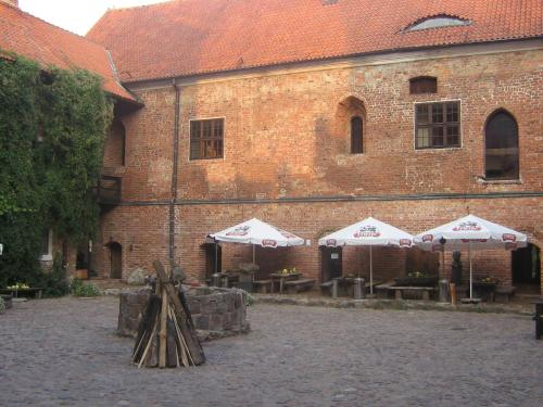 a building with umbrellas and tables in front of it at Zamek Reszel in Reszel