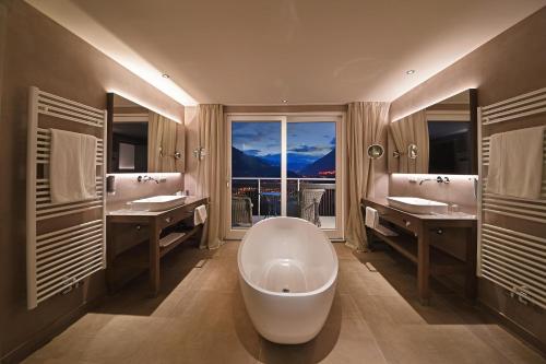 a bathroom with a large tub and a large window at Hotel Patrizia in Tirolo