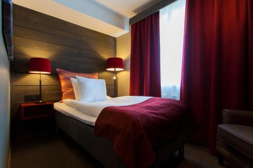 a bedroom with a bed and a window with red curtains at Hotell Nordic in Norrköping