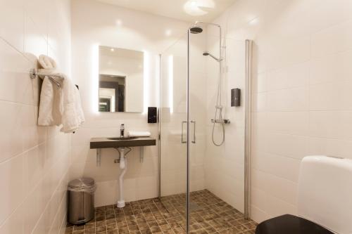 uma casa de banho com um chuveiro e um lavatório. em Hotell Nordic em Norrköping