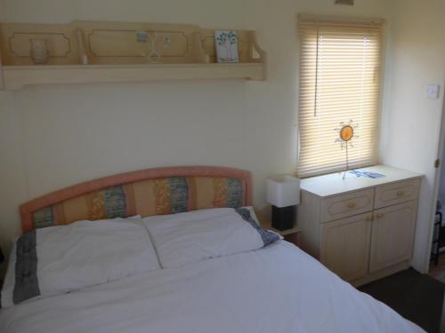 a bedroom with a white bed and a window at Mablethorpe L12 Caravan in Mablethorpe
