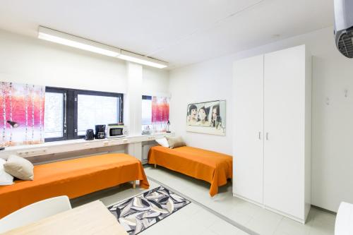 2 camas en una habitación blanca con sábanas de color naranja en Forenom Hostel Vantaa Airport, en Vantaa