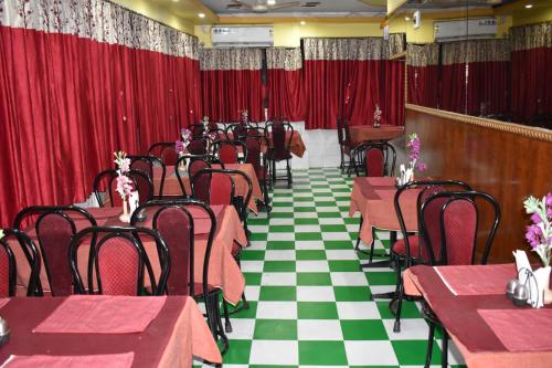 un comedor con mesas, sillas y cortinas rojas en Hotel Airways en Calcuta