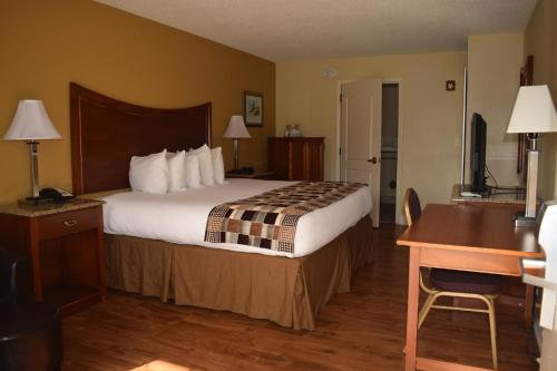 a hotel room with a large bed and a desk at Atkinson Inn & Suites in Lumberton