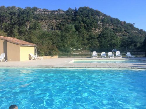 une piscine avec des chaises et un terrain de volley-ball dans l'établissement Les mobil-homes du Moulinage, à Montréal