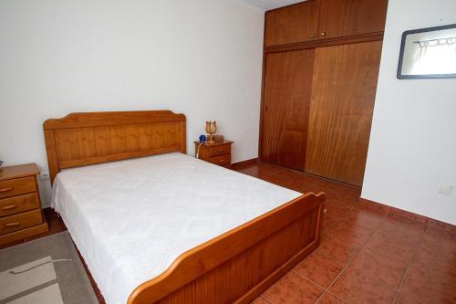 a bedroom with a bed and a wooden cabinet at Casa dos Rui´s in Velas