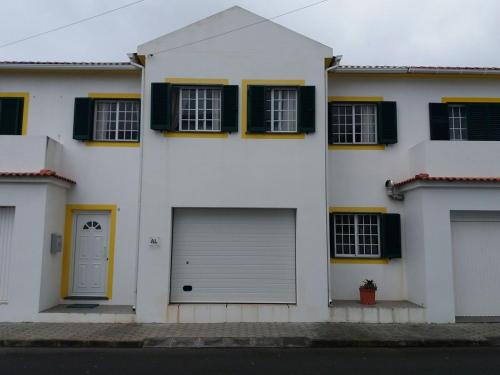 a white house with two garage doors and windows at Casa dos Rui´s in Velas