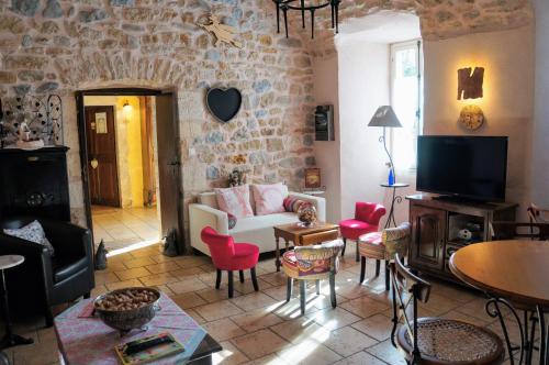 een woonkamer met een bank en stoelen en een tv bij Le Manoir du Raveyron in Vallon-Pont-dʼArc
