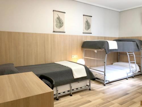 Zimmer mit 2 Etagenbetten und einem Tisch in der Unterkunft Bearan Bar & Rooms in Pamplona