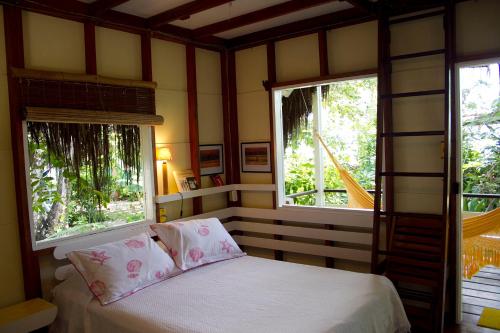 a bedroom with two windows and a bed with white sheets at Pousada Vila Sereia in Ilha de Boipeba