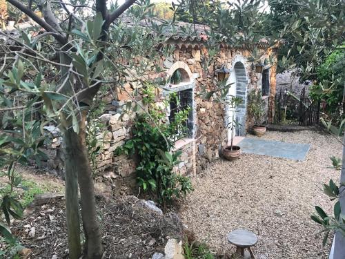 a stone building in a garden with plants at La Maison des Oliviers in Cogolin
