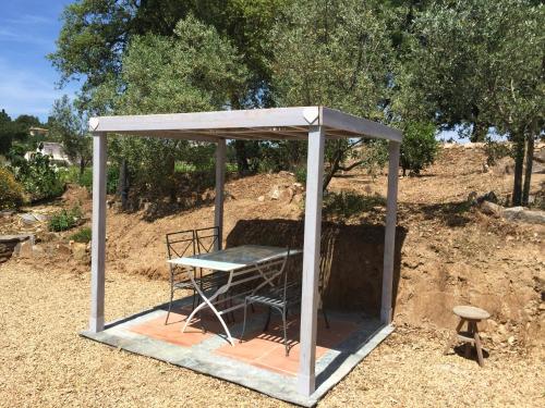a shelter with a table and a chair in it at La Maison des Oliviers in Cogolin