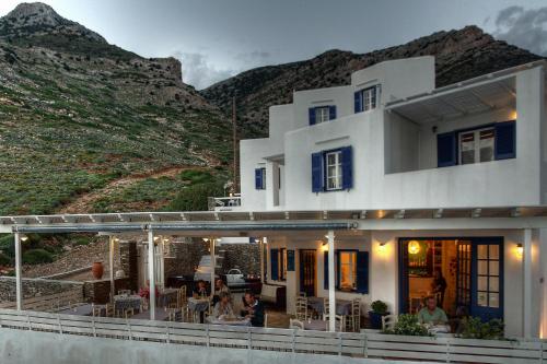 a house with people sitting on a deck with mountains in the background at Delfini in Kamarai