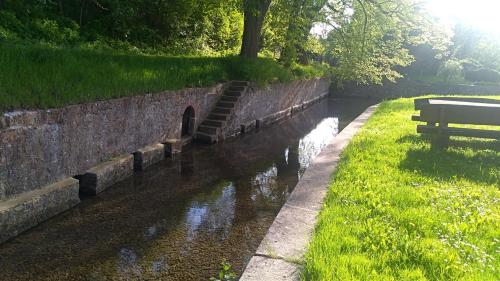a park bench next to a river with a brick wall at Fewo-Sendelbach in Greußenheim