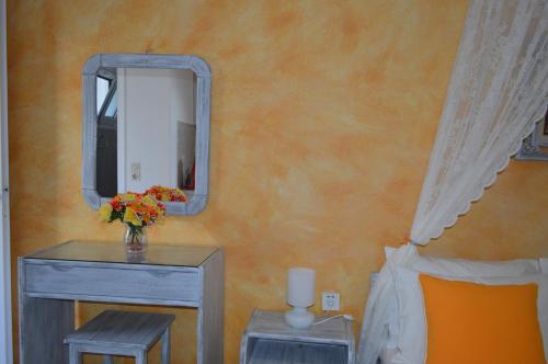 a bedroom with a mirror and a table with a vase of flowers at Kiklamino Sunset Studios in Oia