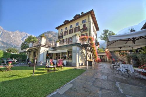 a large building with a patio with chairs and tables at Villa Novecento Romantic Hotel - Estella Hotel Collection & Experience in Courmayeur