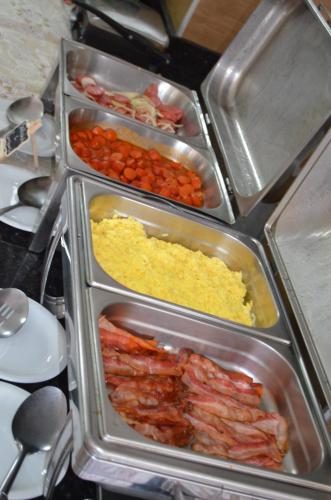 four metal trays filled with different types of food at Presidente Hotel in Poços de Caldas