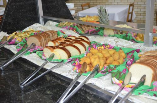 a buffet with sandwiches and other foods and tongs at Presidente Hotel in Poços de Caldas