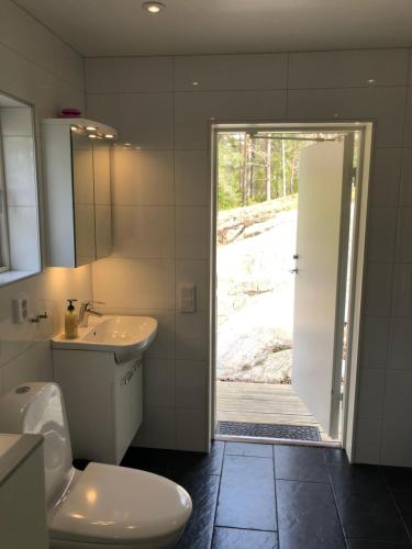 a bathroom with a toilet and a sink and a door at Hällestrand Cottage -Sillen in Strömstad