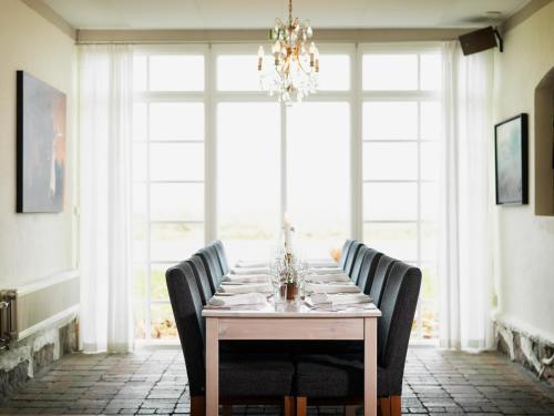 une salle à manger avec une table, des chaises et un lustre dans l'établissement Blåsingsborgs Gårdshotell, à Kivik